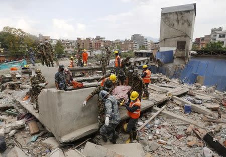 India's National Disaster Response Force (NDRF) personnel and Nepal army soldiers carry a body after being recovered from a collapsed house, after the earthquake in Kathmandu, Nepal April 29, 2015. REUTERS/Adnan Abidi/Files