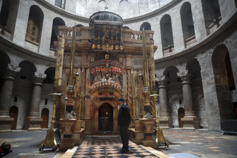 A man stands outside the Holy Edicule, where Chritians belive Jesus Christ was buried, in a deserted church of the Holy Sepulchre in Jerusalem, Sunday, March 15, 2020. Israel imposed sweeping travel and quarantine measures more than a week ago but has seen its number of confirmed coronavirus cases double in recent days, to around 200. On Saturday, the government said restaurants, malls, cinemas, gyms and daycare centers would close. (AP Photo/Mahmoud Illean)