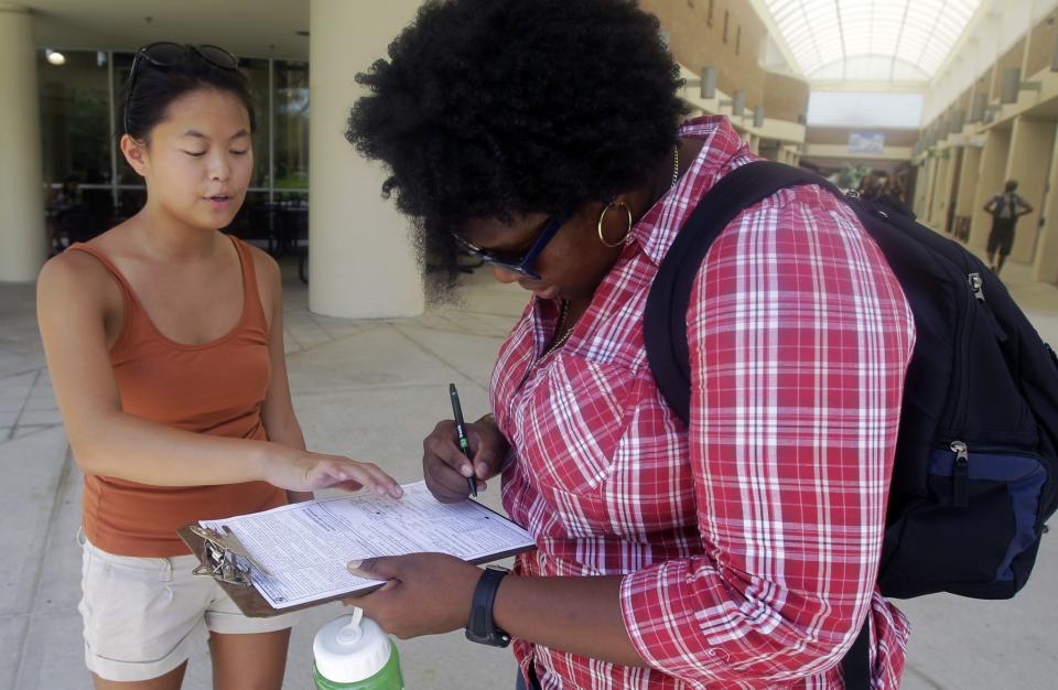 Aubrey Marks, left, helps a University of Central Florida student to register to vote in Orlando, Fla. in 2012. (Photo: John Raoux/AP)