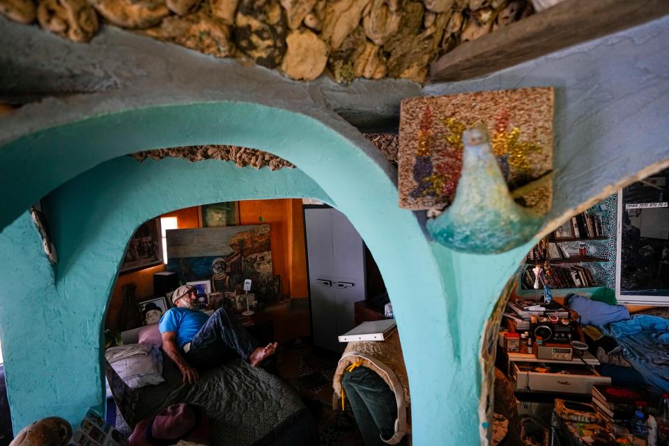 Nissim Kahlon gets up from his bed in his home chiseled out of the sandstone cliffs overlooking the Mediterranean sea in Herzliya, Israel, Wednesday, June 28, 2023.