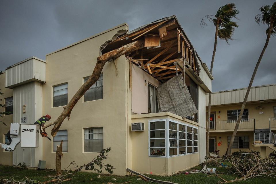 Maximum Services Tree & Landscape workers remove a tree Thursday from one of several now-condemned condominium units at the Kings Point community in west of Delray Beach. A tornado spawned by Hurricane Ian touched down late Tuesday night in the community, causing extensive damage.