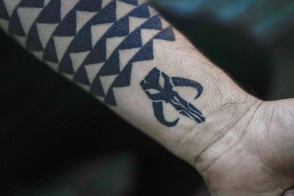 A Jedi Knight Academy member shows their tattoo of the Mythosaur skull emblem, from Star Wars Mandalorian, during lightsaber training at a park in Mexico City, Thursday, June 20, 2024. The academy is a lightsaber combat and choreography school founded in 2019 and a dream come true for fans of Star Wars. (AP Photo/Eduardo Verdugo)