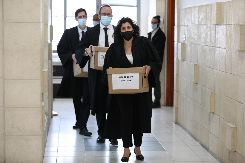 FILE - In this April 5, 2021 file photo, state attorneys carrying prosecution materials in the trial of then Prime Minister Benjamin Netanyahu, at the Jerusalem district court in Jerusalem. Israel's prime minister's office has urged Netanyahu to return dozens of expensive gifts he received while serving in the nation's top job. Netanyahu, Israel's longest-serving prime minister, now opposition leader, has developed a reputation for enjoying a lavish lifestyle, often at taxpayer expense, and is on trial for allegedly accepting expensive gifts from wealthy associates. (Abir Sultan/Pool Photo via AP, File)