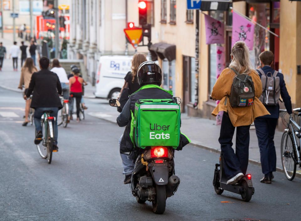 A moped delivery courier of the Ubereats food delivery company rides between bicycles and electric scooters in the Sodermalm neighborhood of Stockholm, Sweden, August 20, 2020. Fredrik Sandberg/TT News Agency/via REUTERS. ATTENTION EDITORS - THIS IMAGE WAS PROVIDED BY A THIRD PARTY. SWEDEN OUT. NO COMMERCIAL OR EDITORIAL SALES IN SWEDEN.