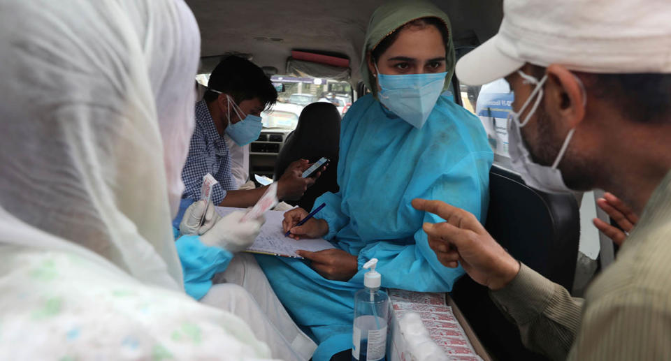 A female health care worker speaks to people.