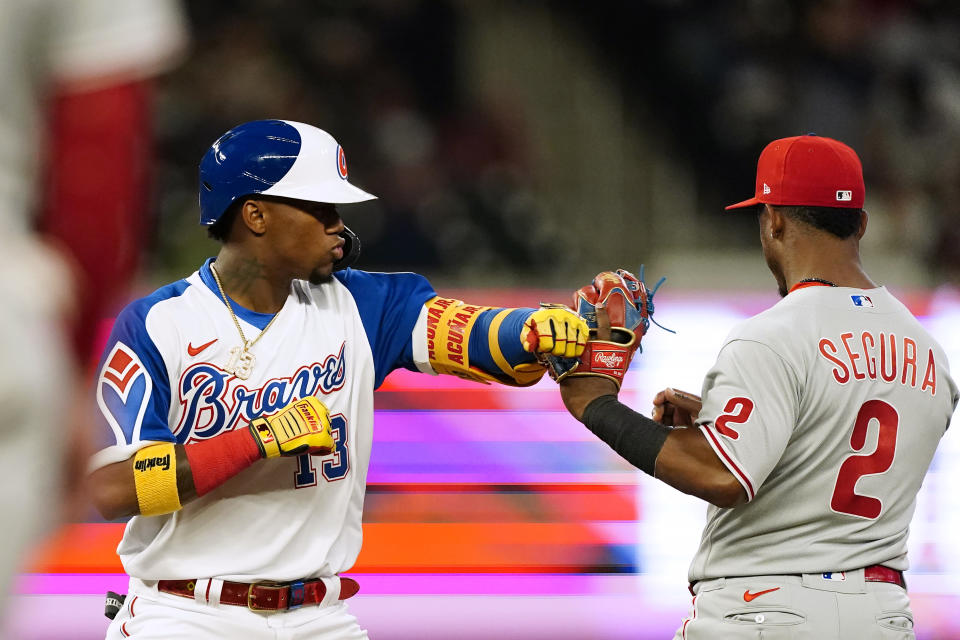 Atlanta Braves' Ronald Acuna Jr. (13) jokes with Philadelphia Phillies shortstop Jean Segura (2) after hitting a double iduringthe third inning of a baseball game Friday, April 9, 2021, in Atlanta. (AP Photo/John Bazemore)