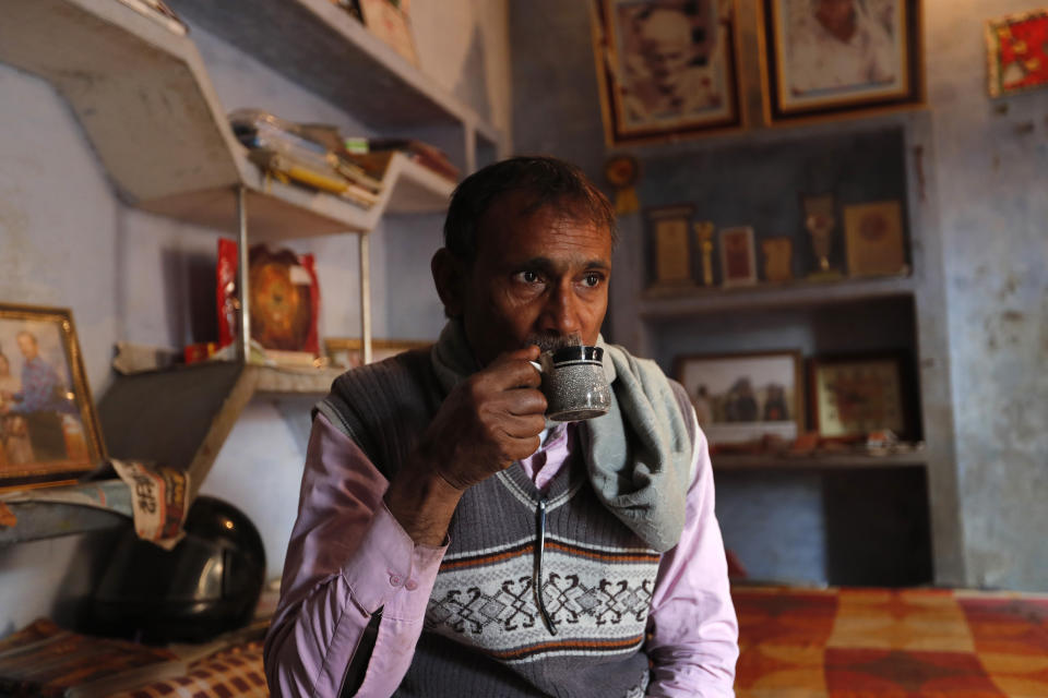 Indian farmer Ram Singh Patel drinks morning tea before leaving his village house to work in the field in Fatehpur district, 180 kilometers (112 miles) south of Lucknow, India, Saturday, Dec. 19, 2020. Patel's day starts at 6 in the morning, when he walks into his farmland tucked next to a railway line. For hours he toils on the farm, where he grows chili peppers, onions, garlic, tomatoes and papayas. Sometimes his wife, two sons and two daughters join him to lend a helping hand or have lunch with him. (AP Photo/Rajesh Kumar Singh)