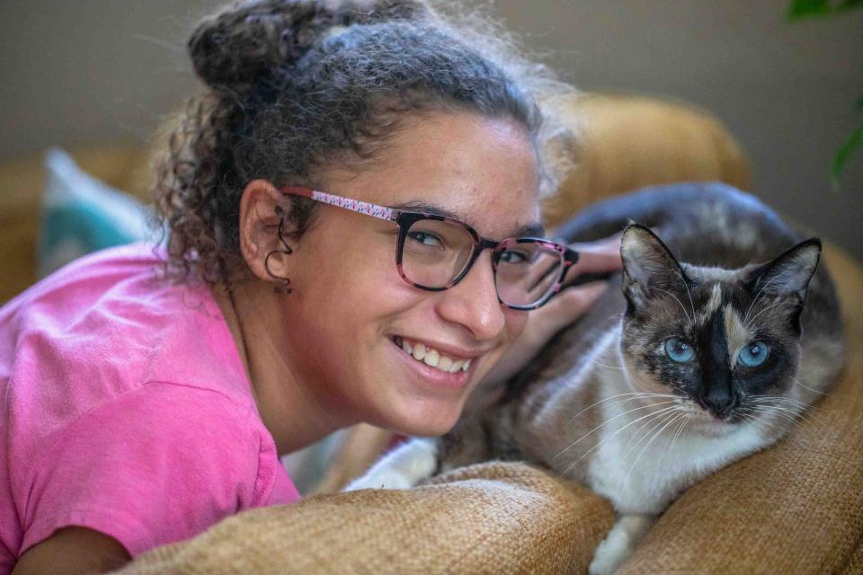 Sakura Hernandez, 13, smiles in her Lake Worth Beach home next to her cat Raya November 2, 2023. Sakura has been diagnosed with cerebral palsy, autism, ADD, and scoliosis.