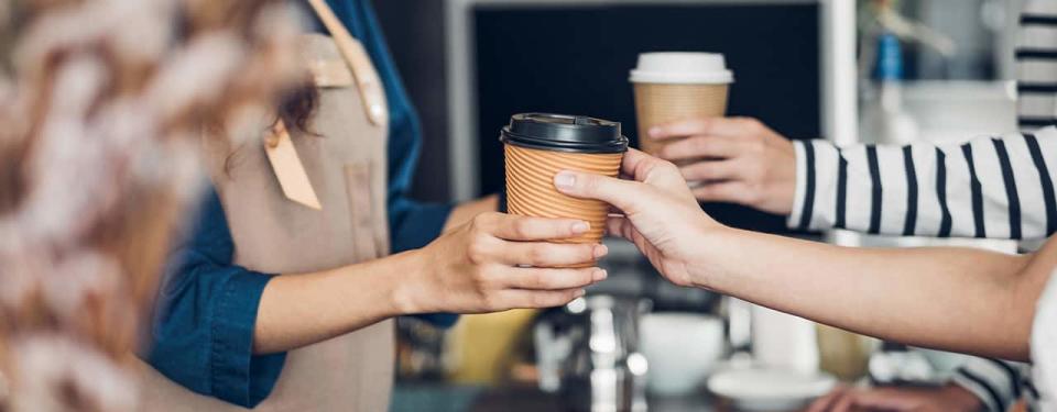 barista handing customer coffee at coffee shop