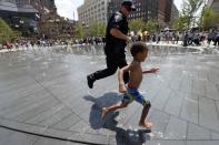 Ein Polizist läuft mit einem kleinen Kind am letzten Tag des republikanischen Parteitags durch einen Brunnen in Cleveland. (Bild: Alex Brandon/AP)