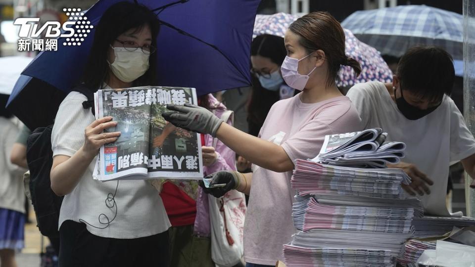 這位女性讀者撐著傘，買了兩份最後一期香港蘋果日報。（圖／達志影像美聯社）