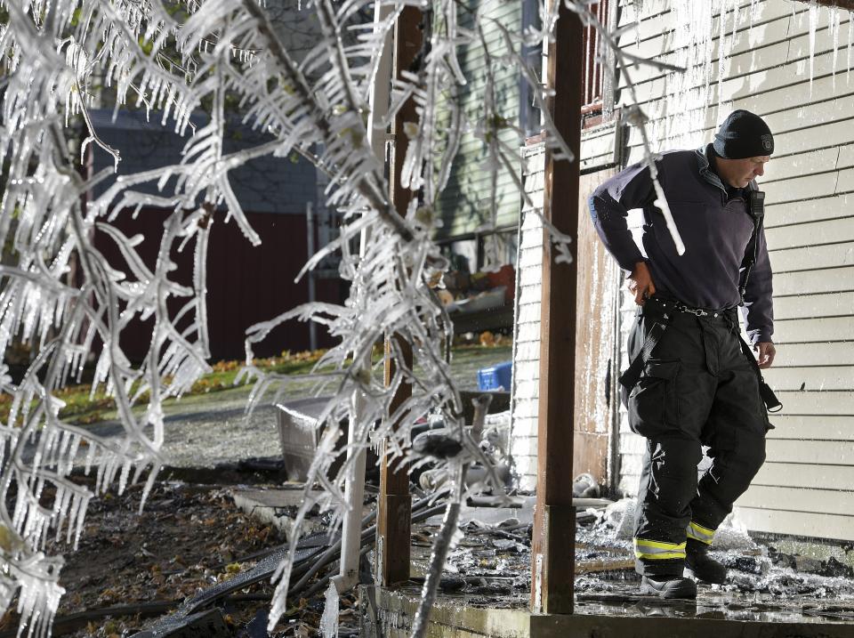 Worcester Fire Department Captain Of Fire Prevention & Investigations Tom Bull, investigates the scene of a overnight fire that killed Lt. Jason Menard, Wednesday, Nov. 13, 2019 in Worcester, Mass. Menard, 39, and his crew became trapped on the top floor of the three-story home after the fire was reported at about 1 a.m., Worcester Fire Chief Michael Lavoie told a news conference. Menard helped two members of his crew escape but he himself was unable to get out. (Christine Peterson/Worcester Telegram & Gazette via AP)