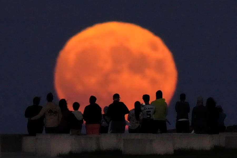 A rare Blue Supermoon rises over Lake Michigan as spectators watch from Chicago’s 31st Street beach Wednesday, Aug. 30, 2023. (AP Photo/Charles Rex Arbogast)