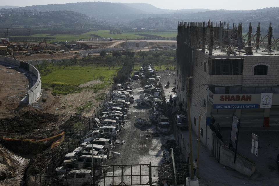 Palestinians look at damaged building and scorched cars, including some that been taken off the road for spare parts, in the town of Hawara, near the West Bank city of Nablus, Monday, Feb. 27, 2023. Scores of Israeli settlers went on a violent rampage in the northern West Bank, setting cars and homes on fire after two settlers were killed by a Palestinian gunman. Palestinian officials say one man was killed and four others were badly wounded. (AP Photo/Majdi Mohammed)