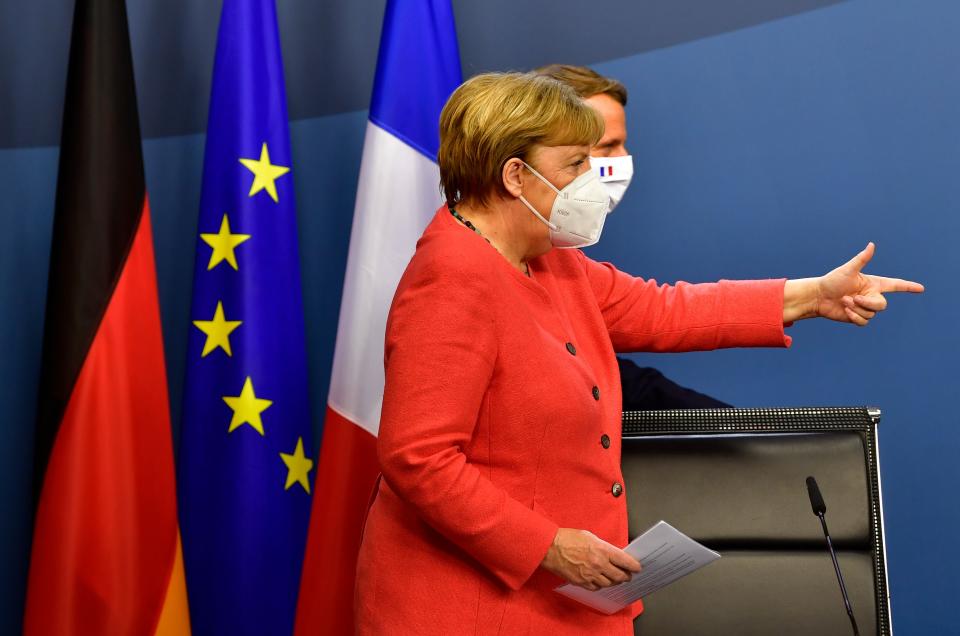 TOPSHOT - German Chancellor Angela Merkel (L) and French President Emmanuel Macron (R) step onstage for a joint press conference at the end of the European summit at the EU headquarters in Brussels on July 21, 2020. - EU leaders approved a 750-billion-euro package to revive their coronavirus-ravaged economies after a tough 90-hour summit on July 21, along with a trillion-euro budget for the next seven years. (Photo by JOHN THYS / POOL / AFP) (Photo by JOHN THYS/POOL/AFP via Getty Images)