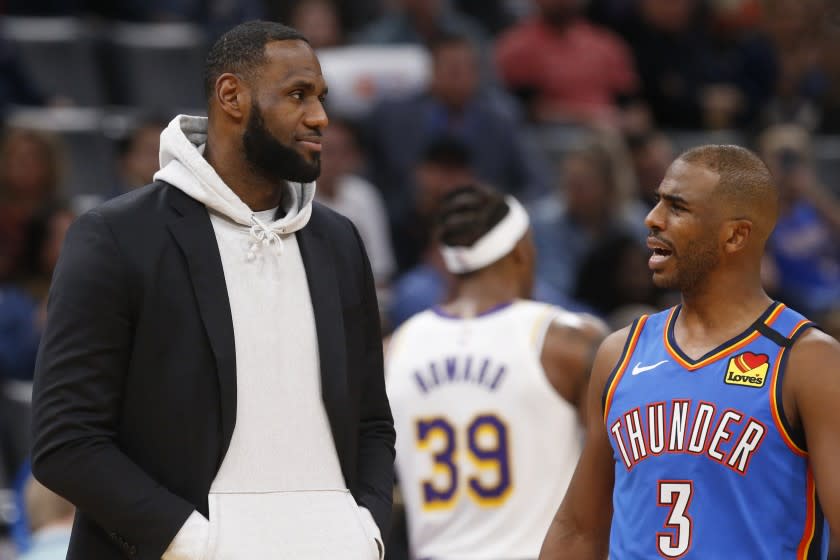 Los Angeles Lakers forward LeBron James, left, talks with Oklahoma City Thunder guard Chris Paul (3) during a timeout in the second half of an NBA basketball game Saturday, Jan. 11, 2020, in Oklahoma City. (AP Photo/Sue Ogrocki)