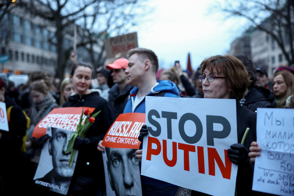 Varias personas sostienen pancartas mientras asisten a una vigilia celebrada frente a la embajada rusa en Berlín tras la muerte del líder opositor ruso Alexei Navalny, Alemania, 16 de febrero de 2024. (REUTERS/Liesa Johannssen)
