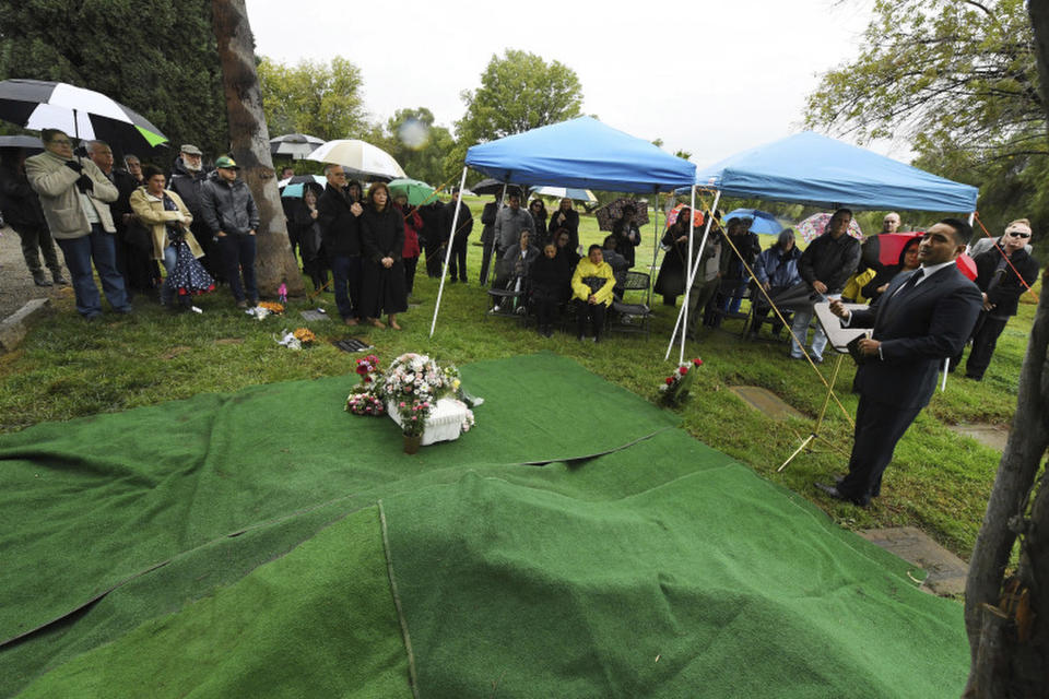 In this Thursday, Dec. 6, 2018, photo mourners gather for the funeral of Baby Jane Doe at Sunnyslope Cemetery in Corona, Calif., as Corona police department Chaplin Jon Castillo, far right, delivers the eulogy Thursday morning. The newborn infant was found in a cardboard box near the 15 freeway in Corona in July. Corona police and fire departments along with others contributed to make the funeral possible for the child. Police are still searching for the person or persons responsible. (Will Lester, Inland Valley Daily Bulletin/SCNG via AP)