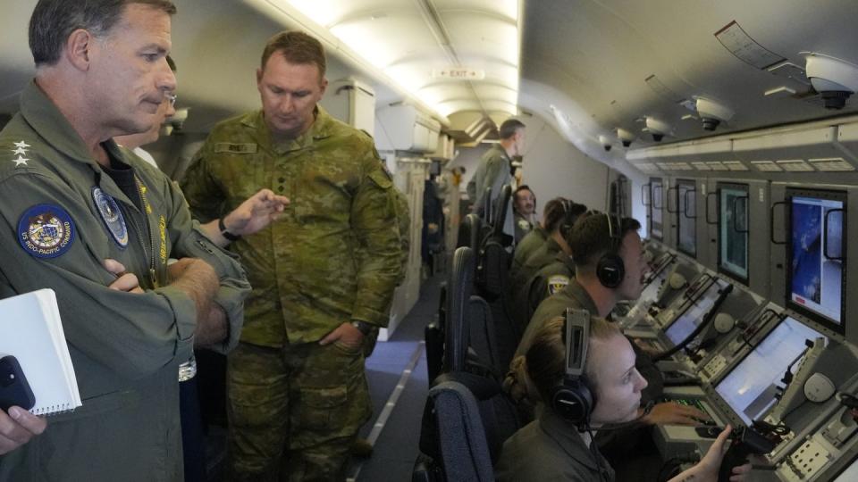 Navy Adm. John Aquilino, left, looks at videos of Chinese structures aboard a U.S. P-8A Poseidon reconnaissance plane on March 20, 2022. (Aaron Favila/AP)