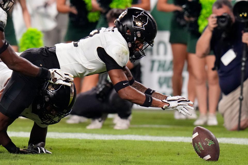 UCF defensive back Justin Hodges (12) dives on a fumble by South Florida quarterback Byrum Brown in the end zone during the first half of an NCAA college football game Saturday, Nov. 26, 2022, in Tampa, Fla. (AP Photo/Chris O'Meara)