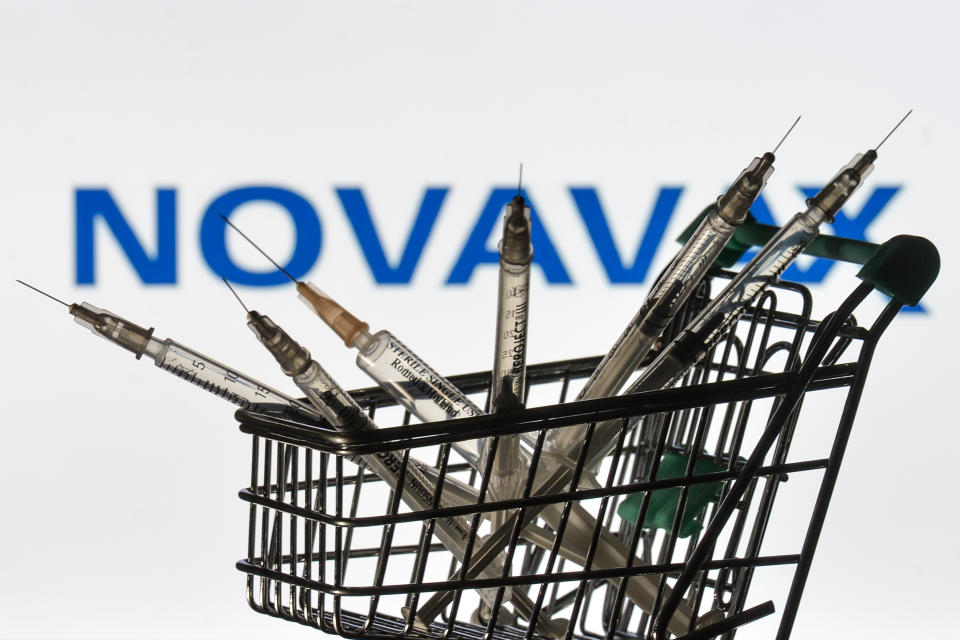 Medical syringes in the mini shopping trolley are seen in front of the Novavax logo displayed on a screen. (PHOTO: Artur Widak/NurPhoto via Getty Images)