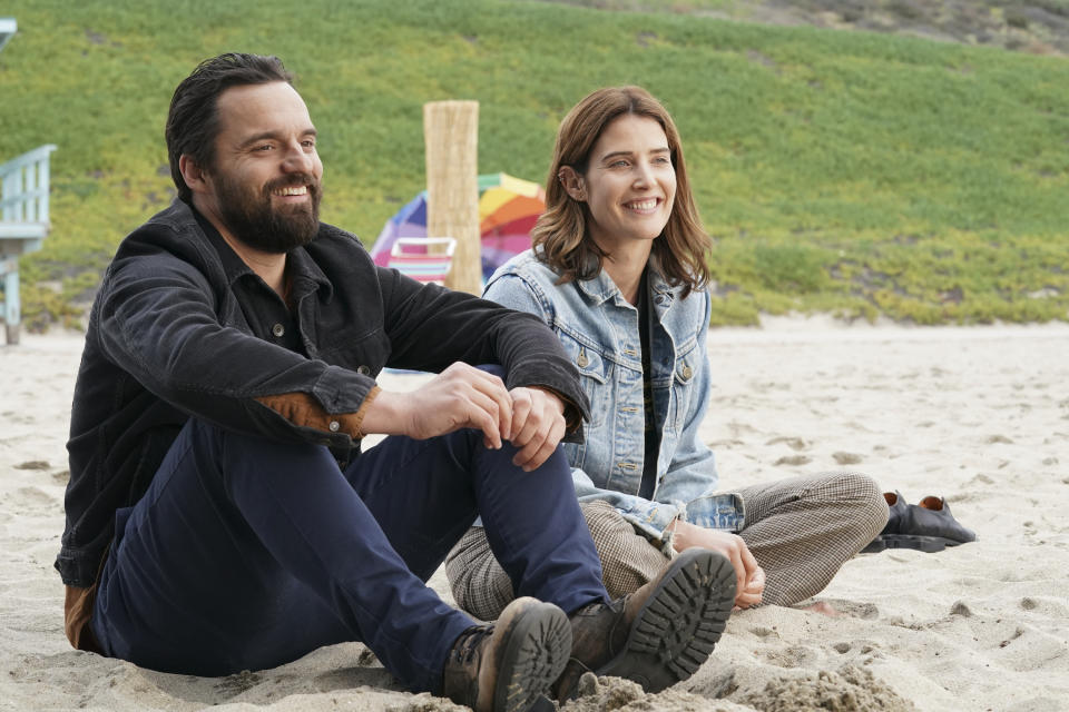 Two people sitting on a beach in a scene from "Stumptown"