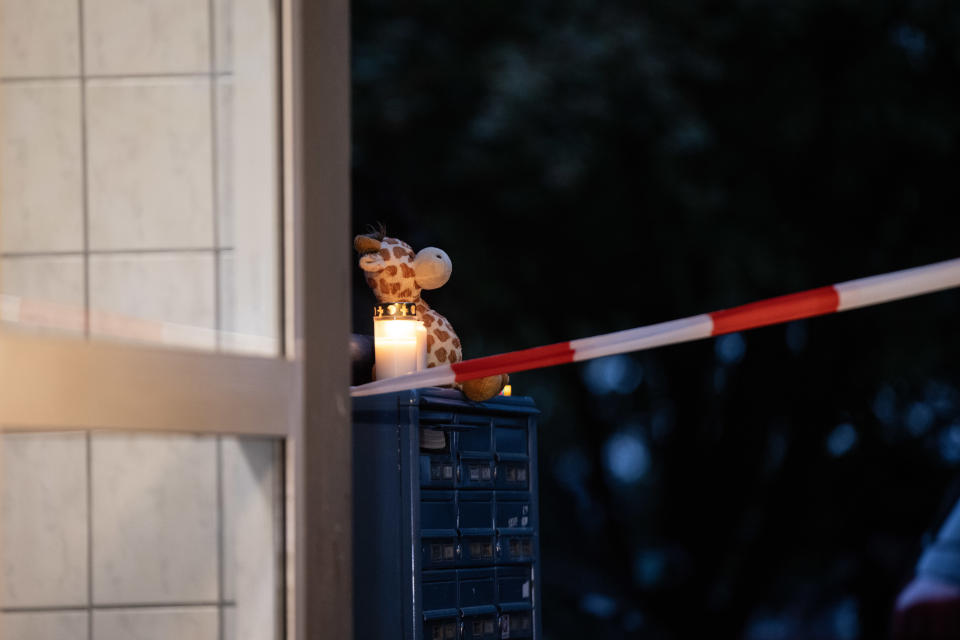 A stuffed toy is placed next to candles on a mailbox at the entrance of the apartment building where five children died.