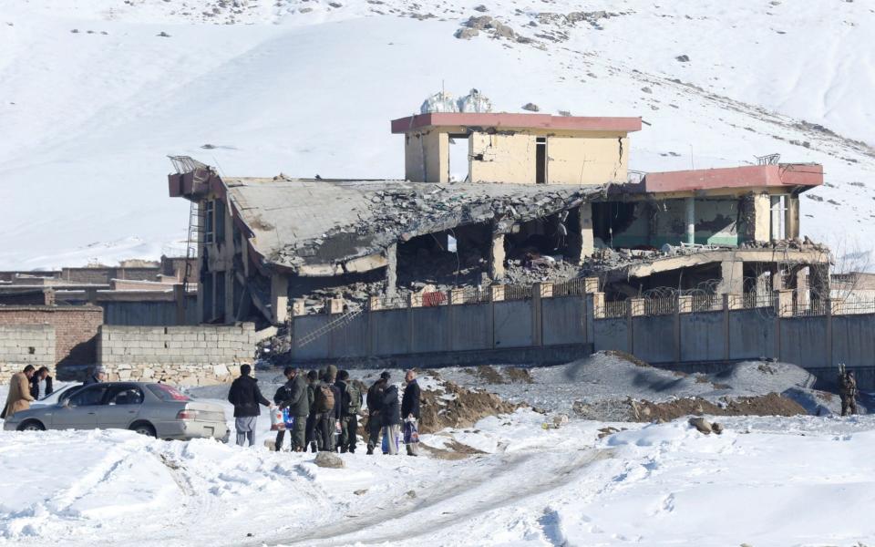 Men stand in front of a collapsed building of a military base after a car bomb attack in Maidan Wardak - REUTERS