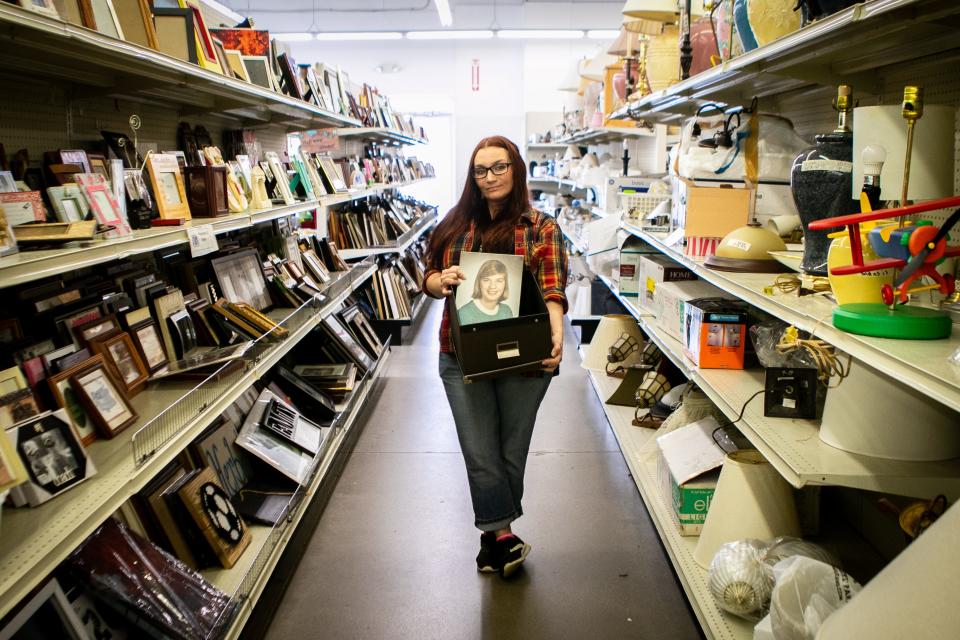 Jenna Thalman, an employee with St. Vincent de Paul, in Milford, holds onto a box of photos she has saved in hopes of reuniting them with their owners. Thalman had recently started setting aside old photos that were donated and posting them to the local neighborhood Facebook group in hopes of finding their proper homes. 