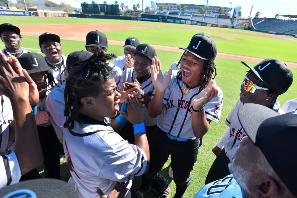 Members of the Ribault Trojans baseball team in their throwback Jacksonville Red Caps baseball uniforms get pumped up before the start of Wednesday's High School Heritage Classic against Raines at 121 Financial Ballpark.