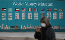 A woman wearing a face mask walks near a board displaying the foreign currencies in downtown Seoul, South Korea, Saturday, Feb. 29, 2020. The coronavirus outbreak's impact on the world economy grew more alarming on Saturday, even as President Donald Trump denounced criticisms of his response to the threat as a "hoax" cooked up by his political enemies. (AP Photo/Lee Jin-man)