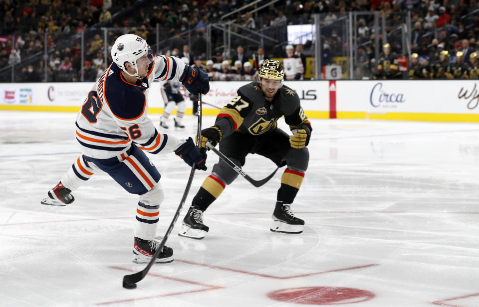 Edmonton Oilers right wing Kailer Yamamoto (56) shoots next to Vegas Golden Knights defenseman Shea Theodore (27) during the third period of an NHL hockey game Friday, Oct. 22, 2021, in Las Vegas. (AP Photo/Steve Marcus)