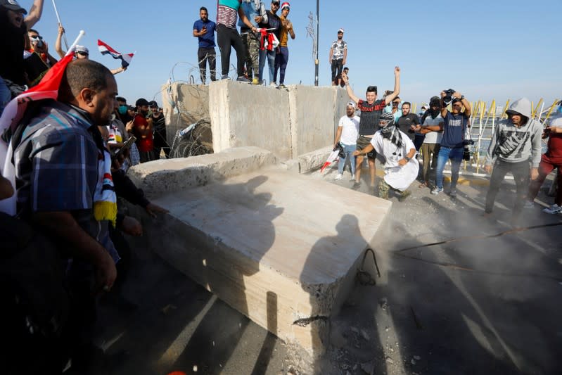 Protesters push down concrete walls during a protest over corruption, lack of jobs, and poor services, in Baghdad