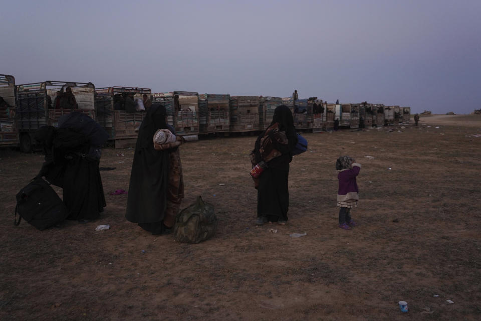 Women and children stand near trucks after being evacuated out of the last territory held by Islamic State militants, outside Baghouz, Syria, Monday, March 4, 2019. Hundreds of people including IS fighters evacuated their last foothold in eastern Syria hours after U.S.-backed Syrian fighters said they were forced to slow their advance because the extremists are using civilians as human shields.(AP Photo/Andrea Rosa)