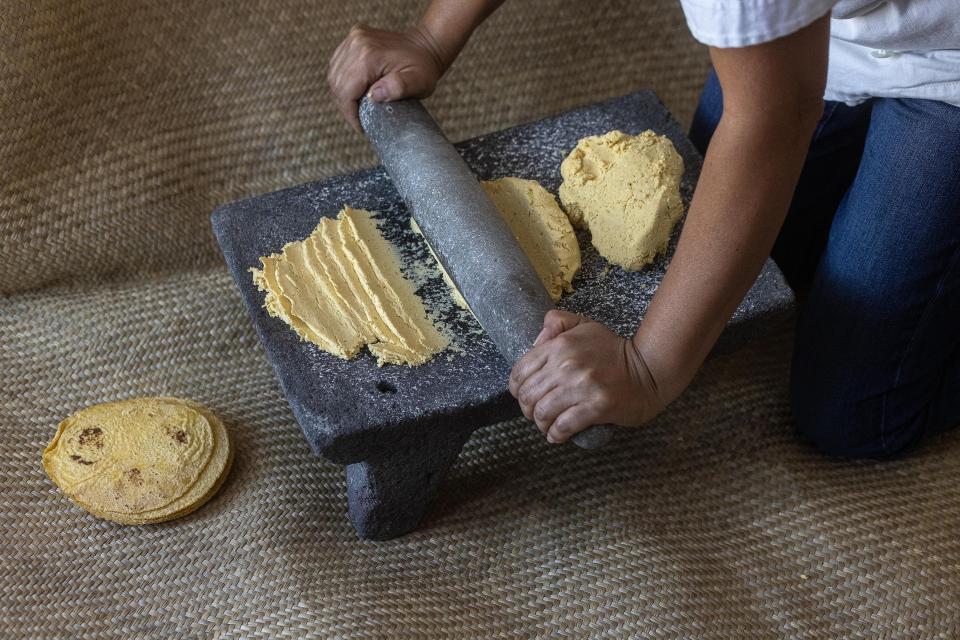 Chef Aurora Garcia Ramos prepares corn masa on a vintage metate mealing stone for Mexican tortillas.