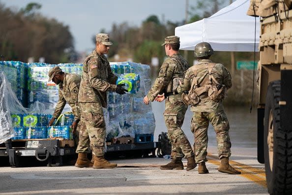 National Guardsmen move cases of water near a flooded road in the wake of Hurricane Ian near the Peace River on October 4, 2022, in Arcadia, Florida. Fifty miles inland, and nearly a week after Hurricane Ian made landfall on the Gulf Coast of Florida, the record-breaking floodwaters in the area are receding to reveal the full effects of the storm.