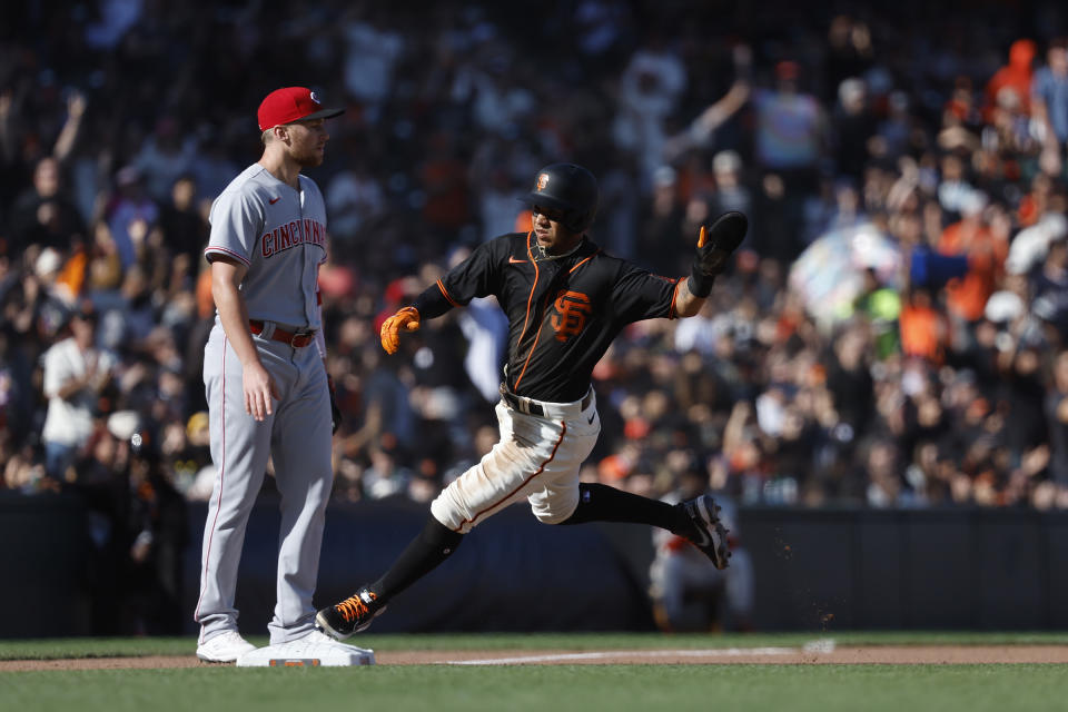 San Francisco Giants' Thairo Estrada, right, runs home to score against Cincinnati Reds third baseman Brandon Drury during the fourth inning of a baseball game in San Francisco, Saturday, June 25, 2022. (AP Photo/Josie Lepe)