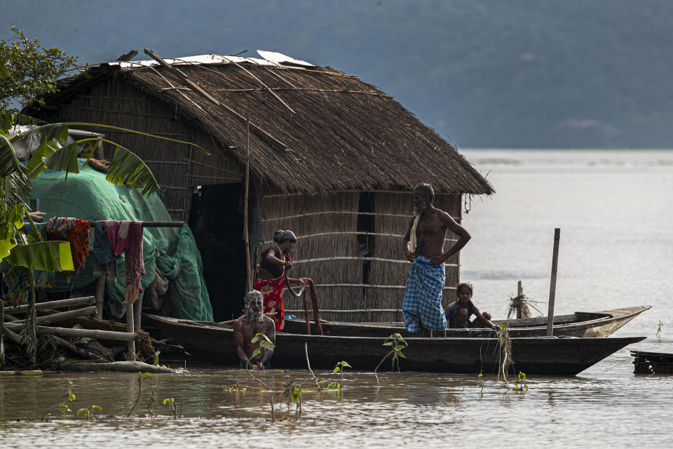 A flood affected family take shelter on boat near their partially submerged house along river Brahmaputra in Morigaon district, Assam, India, Thursday, July 16, 2020. Floods and landslides triggered by heavy monsoon rains have killed dozens of people in this northeastern region. (AP Photo/Anupam Nath)