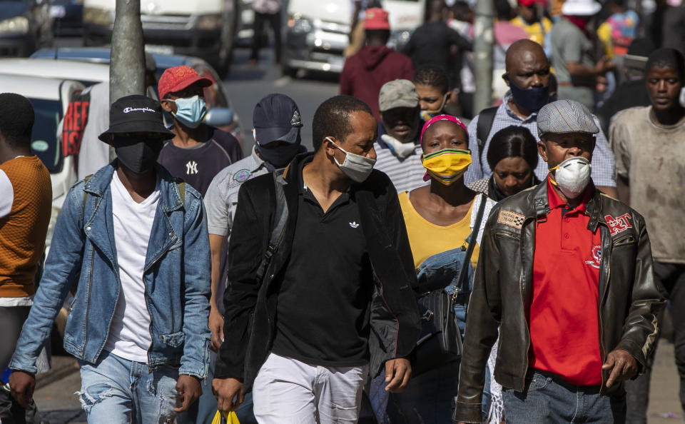 People wearing face masks to protect against coronavirus, walk on the street in downtown Johannesburg, South Africa, Monday, May 11, 2020. (AP Photo/Themba Hadebe)