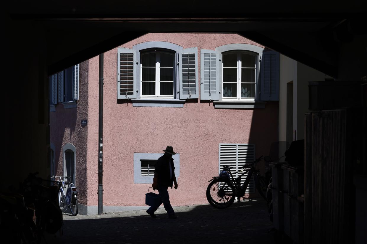 A pedestrian passes a residential apartment building in Zug, Switzerland, on Thursday, April 28, 2022. (Photo: Stefan Wermuth/Bloomberg)