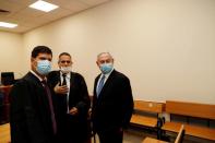 Israeli Prime Minister Benjamin Netanyahu, wearing a face mask, stands next to his lawyers inside the court room as his corruption trial opens at the Jerusalem District Court