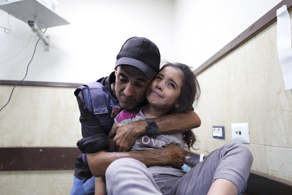 A Palestinian journalist comforts his niece wounded in an Israeli strike on her family home in Nusseirat refugee camp, in a hospital in Deir el-Balah, Gaza Strip, Sunday, Oct. 22, 2023. (AP Photo/Ali Mahmoud)