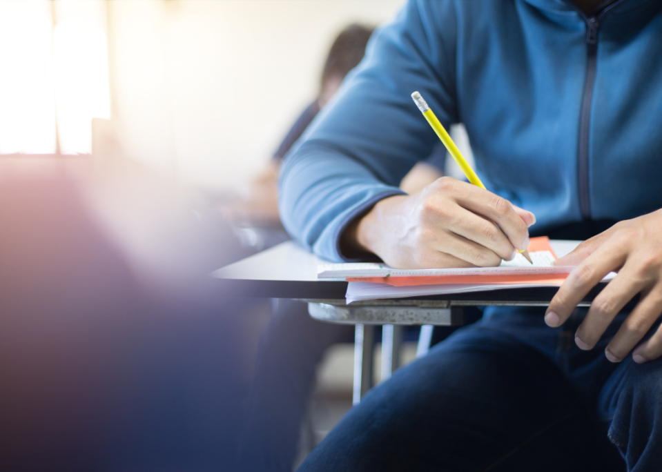 A closeup of a student taking notes in class.