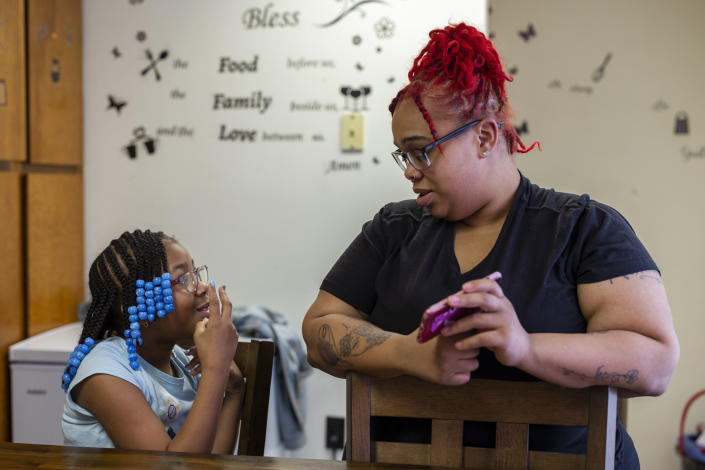 Ashley Martin quizzes her daughter, Ke'Arrah Jessie, 9, on multiplication using an app on her phone in their kitchen in Niagara Falls, N.Y., on Monday, April 3, 2023. Last year's transition back to in-person school was rocky, her mother said. She finished behind in math and reluctant to read. (AP Photo/Lauren Petracca)