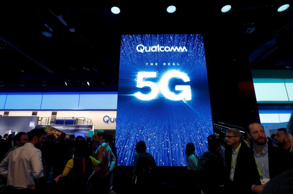 FILE PHOTO: People walk by a video display promoting 5G connectivity at the Qualcomm booth during the 2019 CES in Las Vegas, Nevada, U.S. January 8, 2019. REUTERS/Steve Marcus/File Photo  