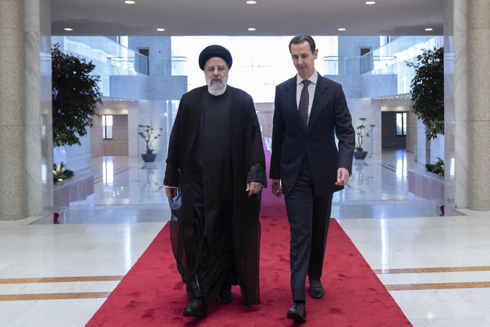 In this photo released by the official Facebook page of the Syrian Presidency, Syrian President Bashar Assad, right, walks with Iranian President Ebrahim Raisi at the presidential palace in Damascus, Syria, Wednesday, May 3, 2023. (Syrian Presidency via Facebook via AP)