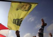 Supporters of the Muslim Brotherhood and ousted Egyptian President Mohamed Mursi, carrying a flag with Mursi's image, shout slogans against the military and interior ministry, while gesturing with four fingers, during a protest in front of riot policemen outside the police academy, where Mursi's trial will take place, on the outskirts of Cairo, November 4, 2013. Mursi arrived at a Cairo police academy on Monday to face trial in what opponents of the army-backed government say is part of a campaign to crush his Muslim Brotherhood and revive a police state. The "Rabaa" or "four" gesture is in reference to the police clearing of the Rabaa al-Adawiya protest camp on August 14. REUTERS/Amr Abdallah Dalsh (EGYPT - Tags: POLITICS CIVIL UNREST)