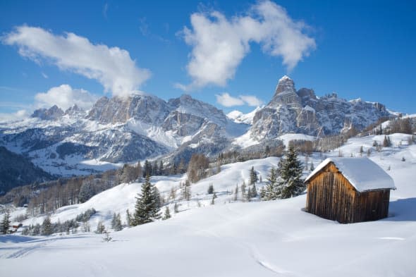 Mounts Lavarella and Conturines behind a pair of barns at the Alta Badia ski resort near Corvara, Dolomites, South Tyrol, Italy