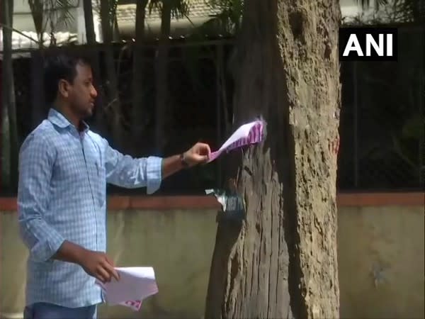 Vinod Kartavya removes a poster from a tree in Bengaluru. (Photo/ANI)