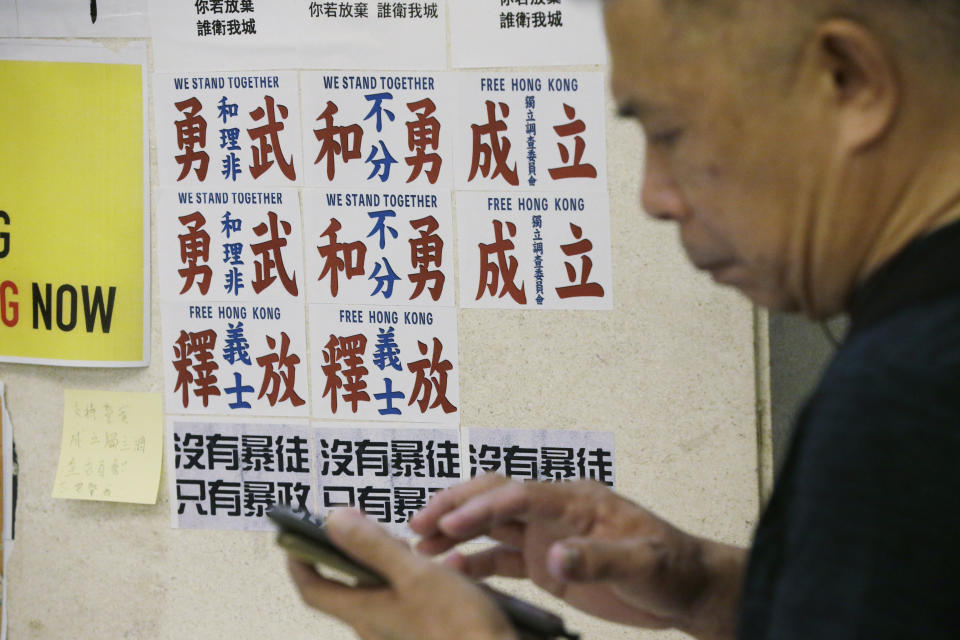 A man walks past the posters with Chinese words read "Peaceful protesters and frontliners stand together" at a shopping mall in Hong Kong, Sunday, Nov. 3, 2019. (AP Photo/Dita Alangkara)